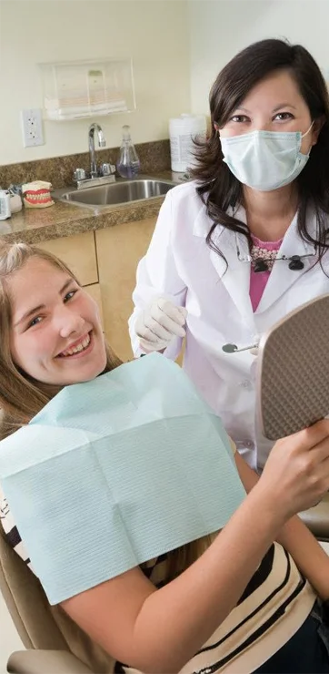 Dr. Tina Le examining a young, smiling patient's teeth